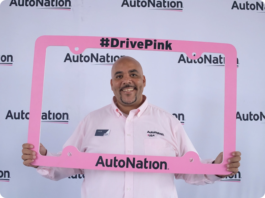 A man standing behind a drive pink license plate frame